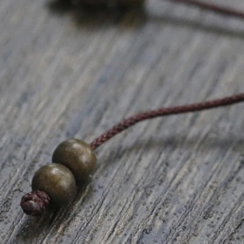 Red string wealth bracelet with copper beads stacked with other jewelry