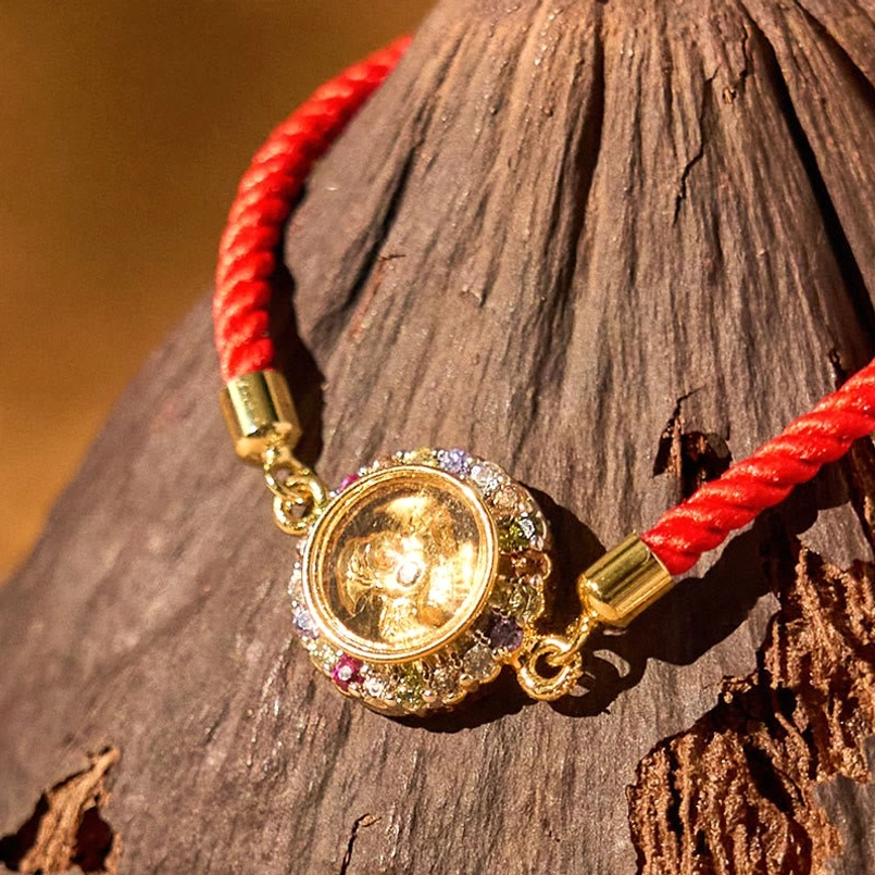 Close-up of rotatable copper windmill charm on red string bracelet