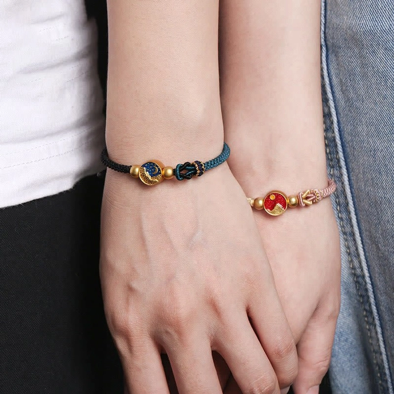 Two matching handmade couple bracelets with black-navy and pink-beige woven rope styles featuring enamel pendants