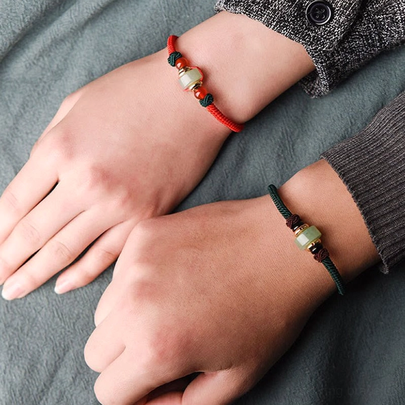 Matching couple tibetan green aventurine and red string luck bracelets with gold toggle hardware, top-down view