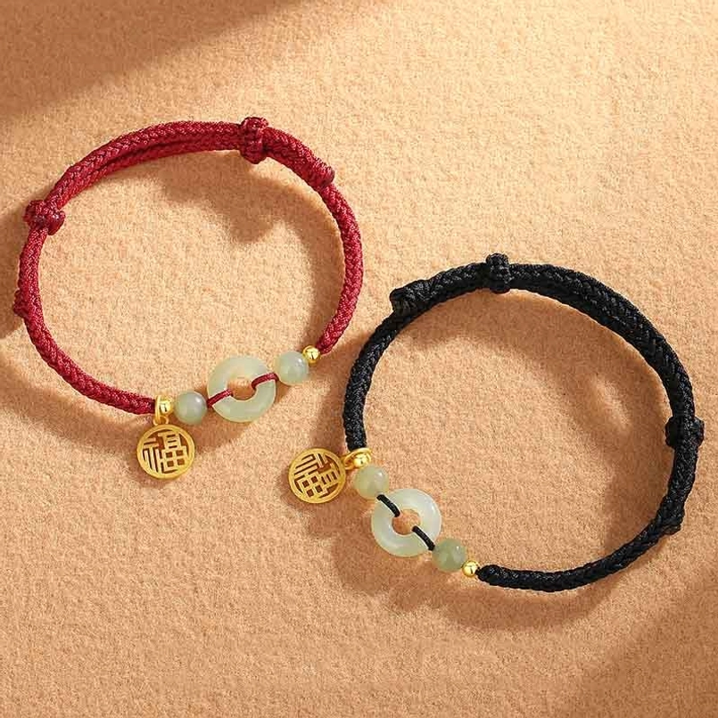 Couple red and black Hetian jade Fu charm bracelets flat lay on suede background
