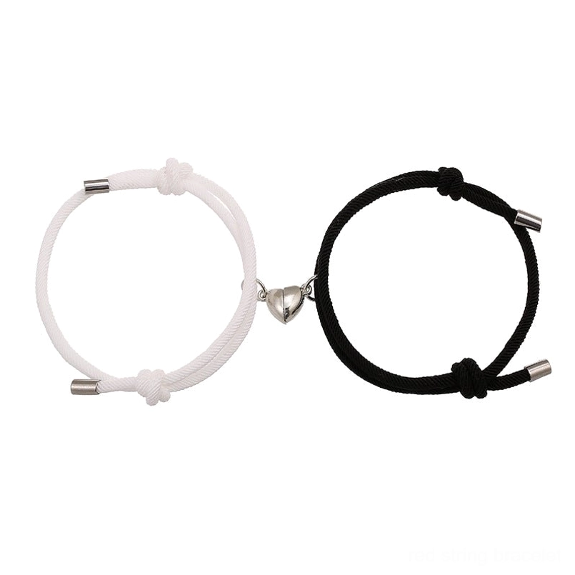 Magnetic couple red string bracelets set with heart clasps, black and white woven rope, flat lay view