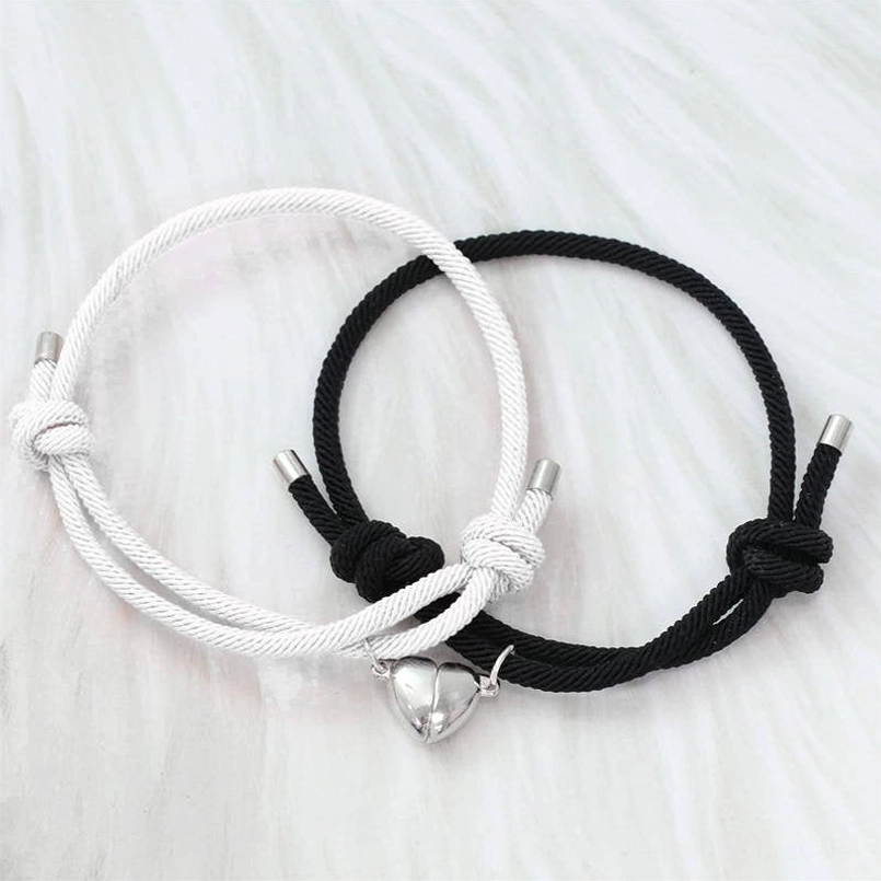 Intertwined magnetic couple red string bracelets on fluffy white background, heart magnetic pendant