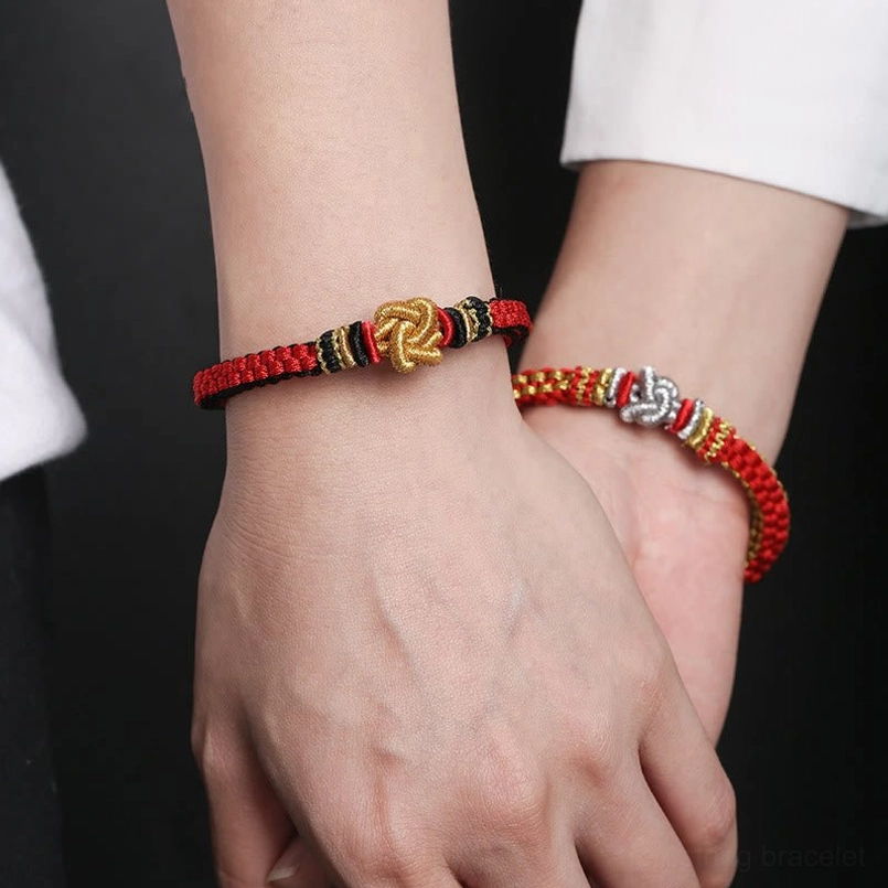 Couple wearing matching red string true love knot bracelets on wrists close-up view