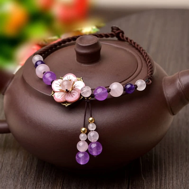 Close-up front view of pink crystal flower charm with purple amethyst beads and rose quartz details