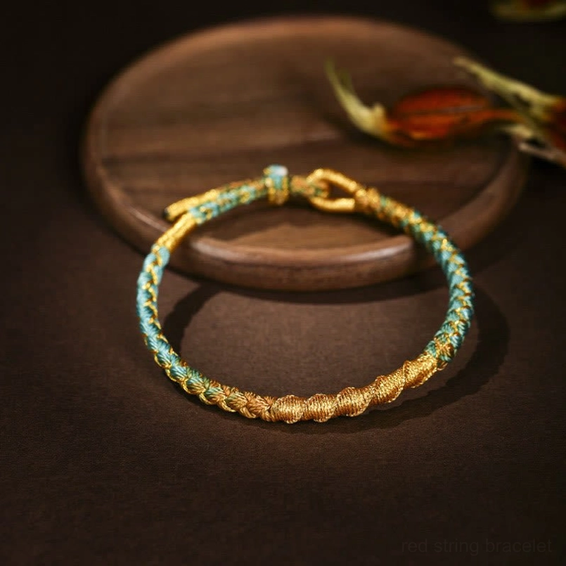 Blue teal gold woven Tibetan bracelet with braided rope texture and adjustable knot on wooden tray