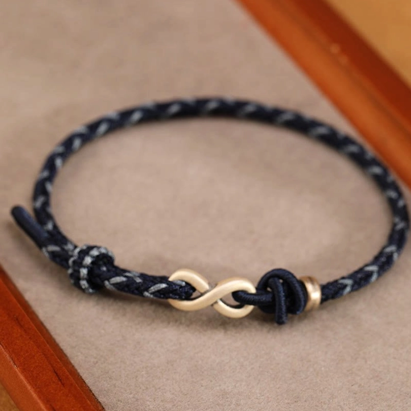 Angled close-up of dark blue polished woven rope endless knot bracelet with silver hardware