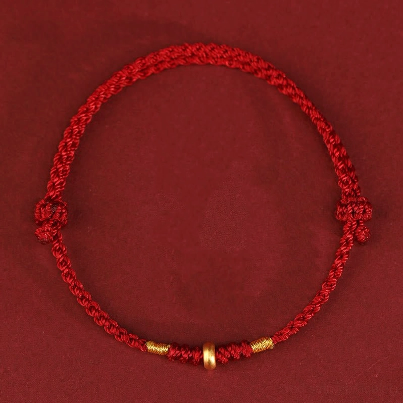 Dark red braided lucky bracelet with adjustable gold bead knots flat lay