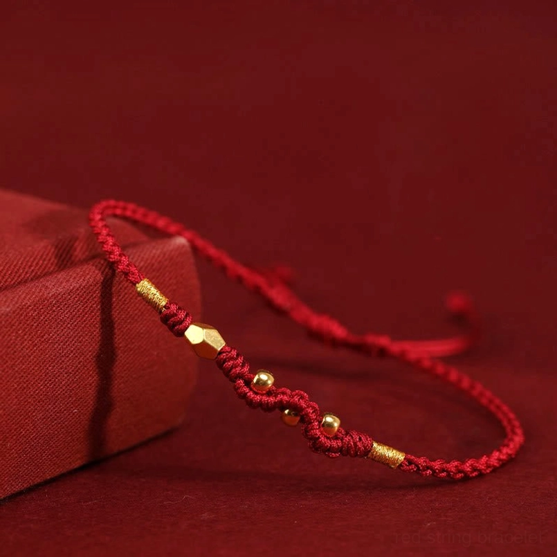 Dark red 999 gold year of the snake red string bracelet on wine red background with gift box