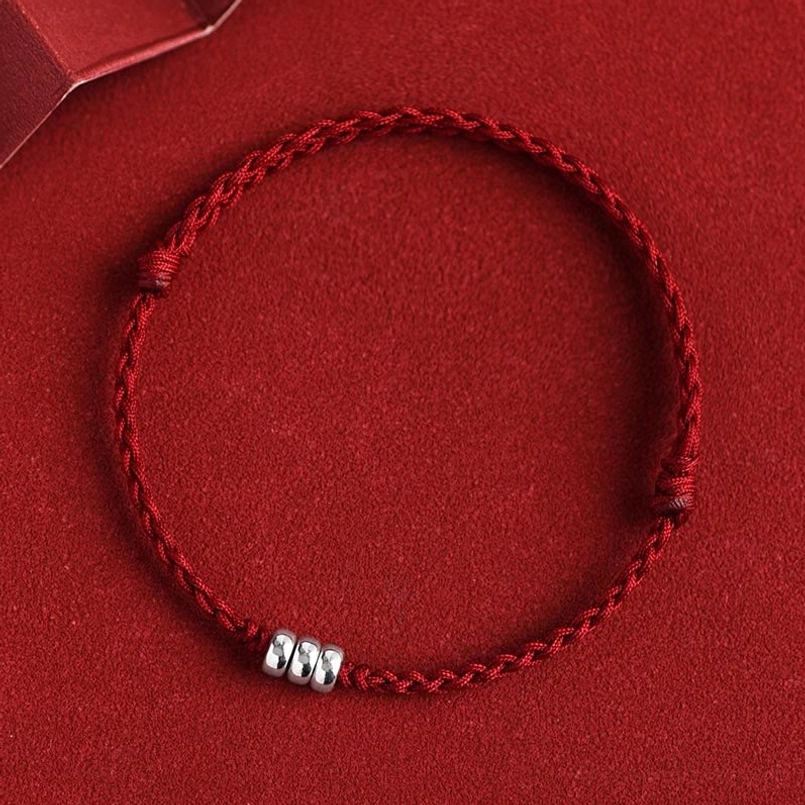 Dark red woven protection bracelet featuring silver beads and adjustable knots, top-down view