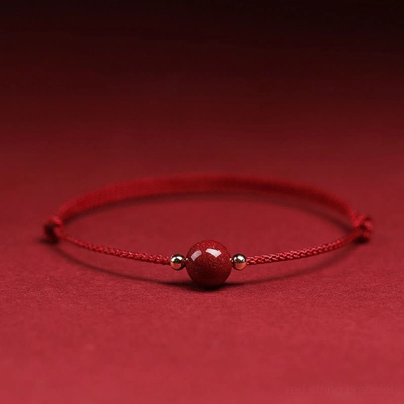 Single dark red cinnabar bead bracelet with metal accents on solid red background