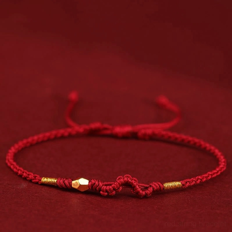 Dark red 999 gold year of the snake red string bracelet flat lay on red background