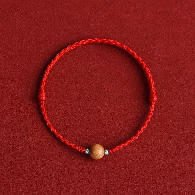 Dark red braided peach wood bead bracelet with protective cord - close-up top view