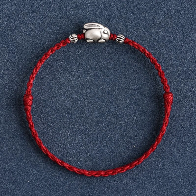 Dark red string silver rabbit bracelet with charm on dark blue fabric