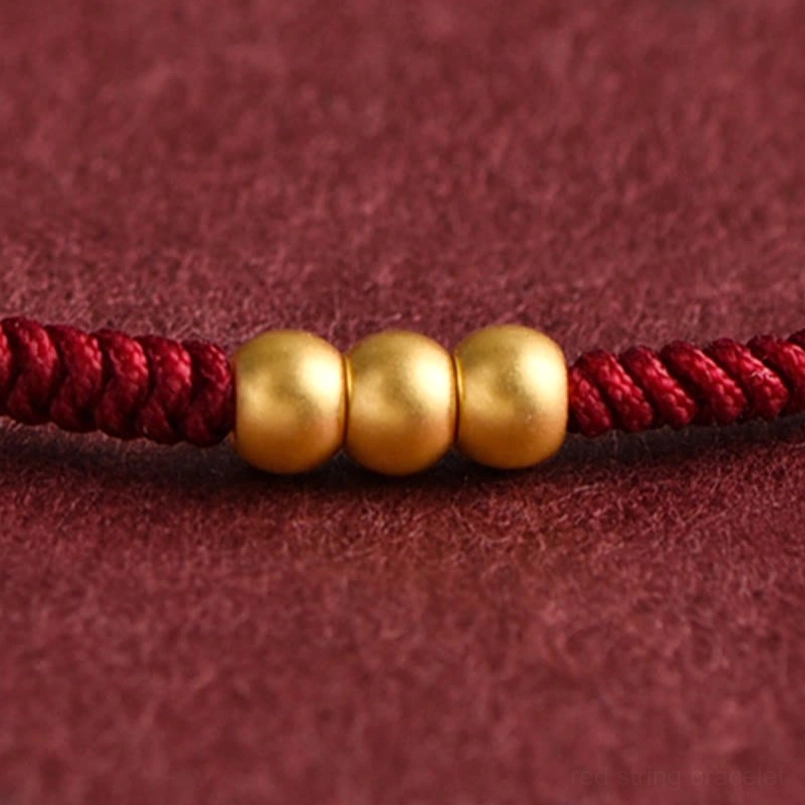 Close up of dark red braided string with 3 999 gold beads
