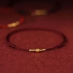 Dark red braided red string bracelet with 925 sterling silver golden bead accent on velvet