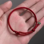 Overhead view of dark red string jade bracelet resting on human palm