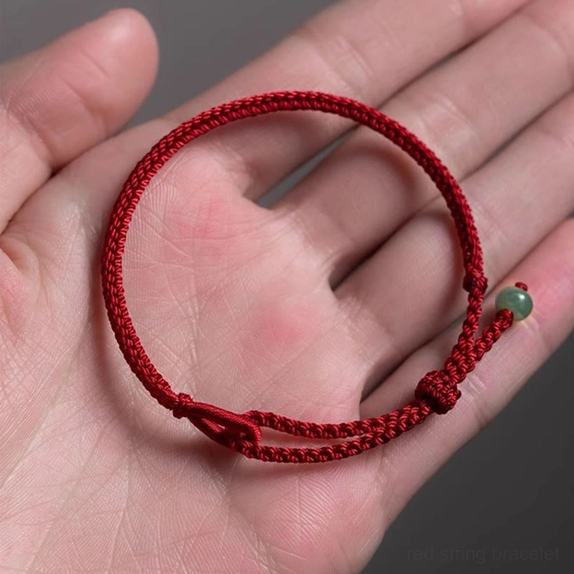 Overhead view of dark red string jade bracelet resting on human palm