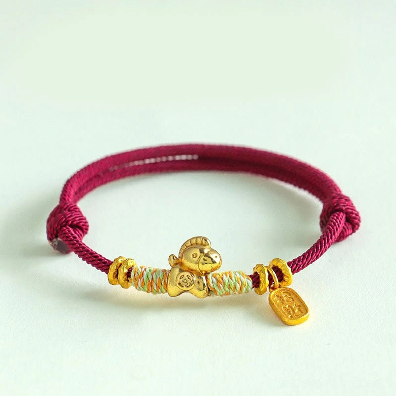 Dark red braided zodiac horse bracelet with gold charm light green background