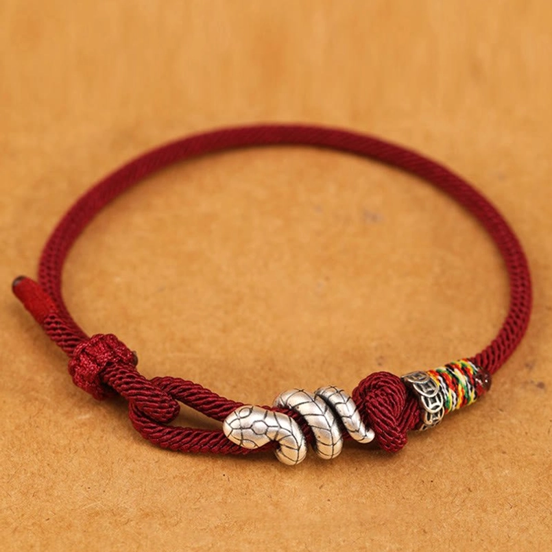 Burgundy red string snake bracelet with silver snake bead and pull knot, top-down flat lay