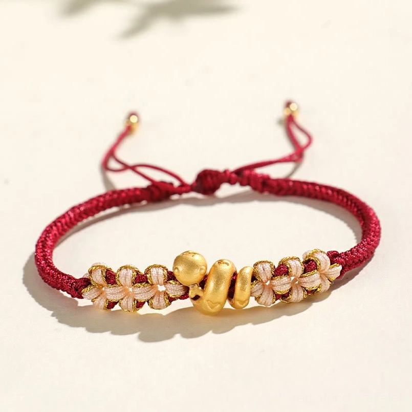 Overhead close up view of dark red braided bracelet with gold snake bead details