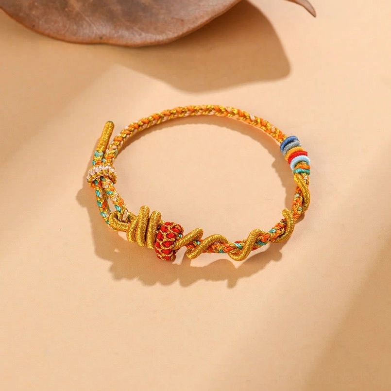 Delicate handmade red string bracelet with woven knots and colorful trim accents