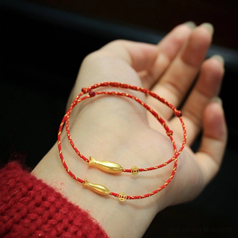 Hand holding double koi fish red string bracelets with gold charms matching red sweater