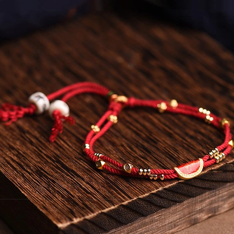 Double layer red rope bracelet with cinnabar dumpling charm on dark wooden board