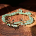 Double layer green aventurine bamboo red string bracelet on wooden tabletop