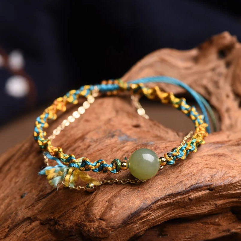 Blue and gold double-layer jade lucky bracelet with tassel charm on wooden background