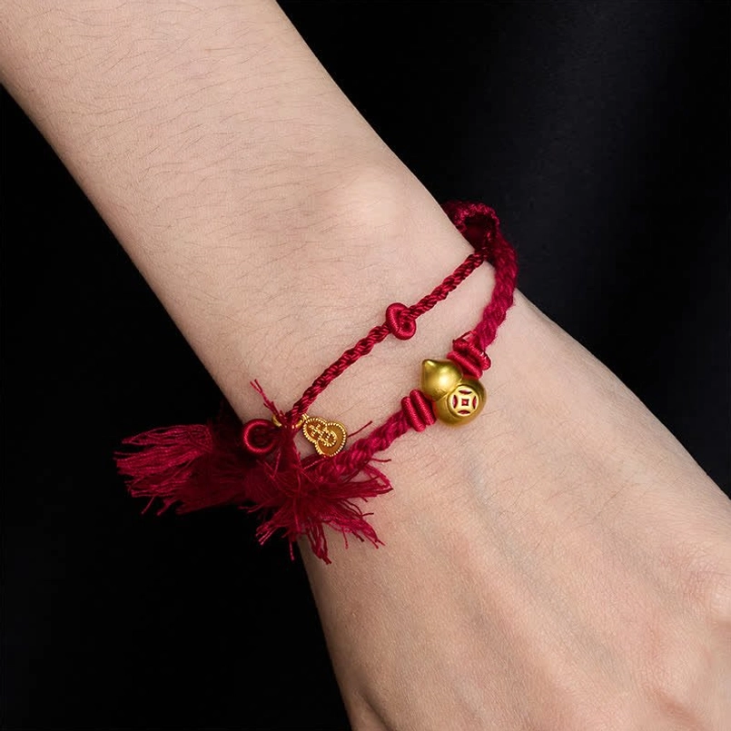 Double strand red string bracelet with gourd charm worn on human wrist close up