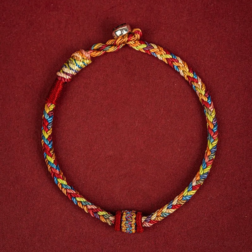 Handmade colorful festival protection bracelet with metal clasp and central decorative knot on fabric backdrop