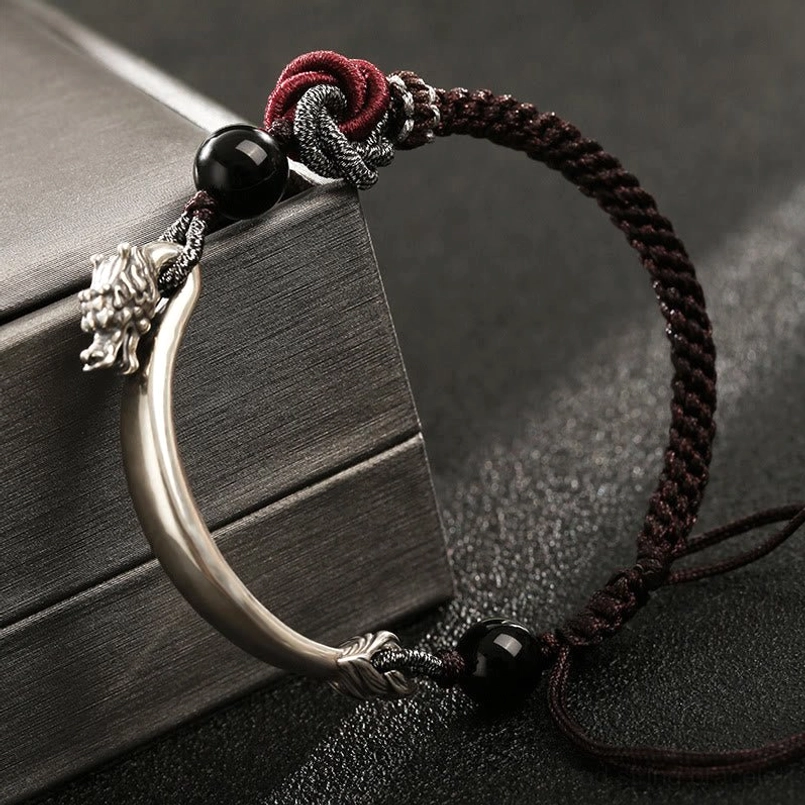 Close-up side view of 925 silver dragon charm accent on braided bracelet with black beads