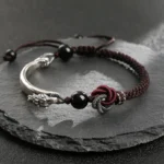 925 sterling silver dragon bracelet handcrafted with braided cord and mandala knot detail on dark slate background