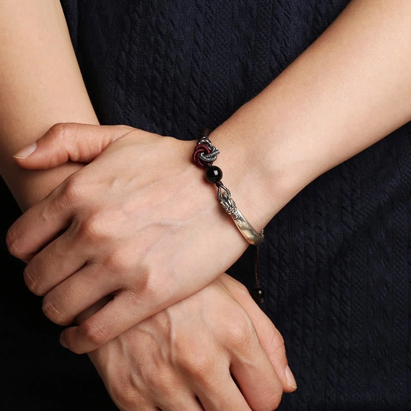 Lifestyle photo of 925 silver dragon bracelet worn on left wrist against dark knit clothing