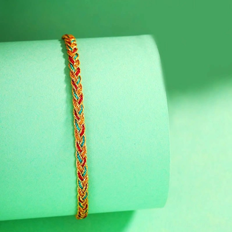 Multicolor dragon scale braid string bracelet hung vertically on green prop displaying twisted rope texture