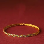 Handmade multicolor dragon scale braid string bracelet with gold, red and blue twisted pattern on burgundy background