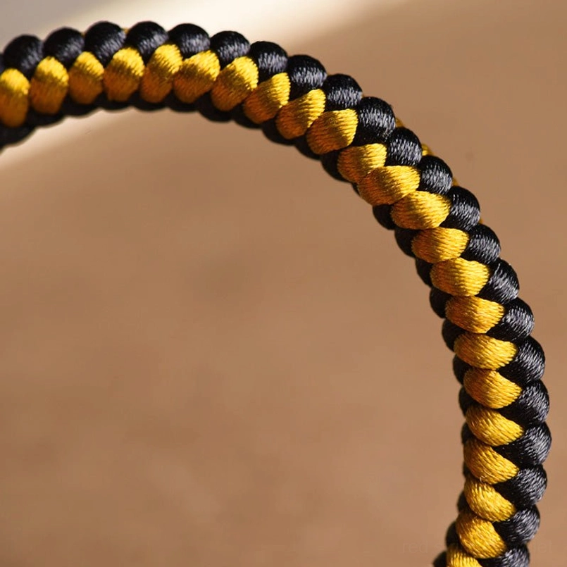Dragon scale braid extreme close-up showing intricate black-gold silk cord texture and weaving pattern