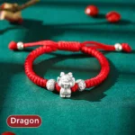 Dragon Chinese zodiac 999 sterling silver red string bracelet flat lay with emerald green background and decorative beads
