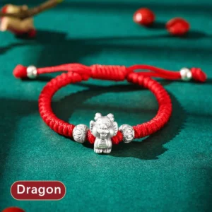 Dragon Chinese zodiac 999 sterling silver red string bracelet flat lay with emerald green background and decorative beads