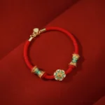 Dunhuang 925 sterling silver lotus drum red string bracelet flat lay on dark red fabric
