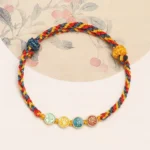 Dunhuang braided string bracelet with multicolor woven rope and enamel character pendants - top view