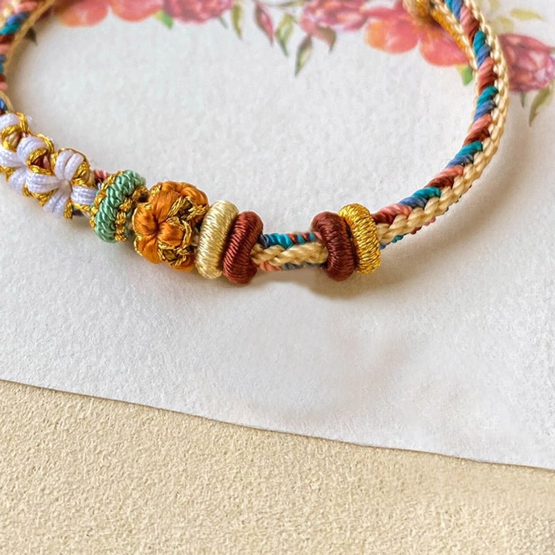Close-up detail of handwoven peach blossom knot on Dunhuang bracelet showing intricate flower craftsmanship