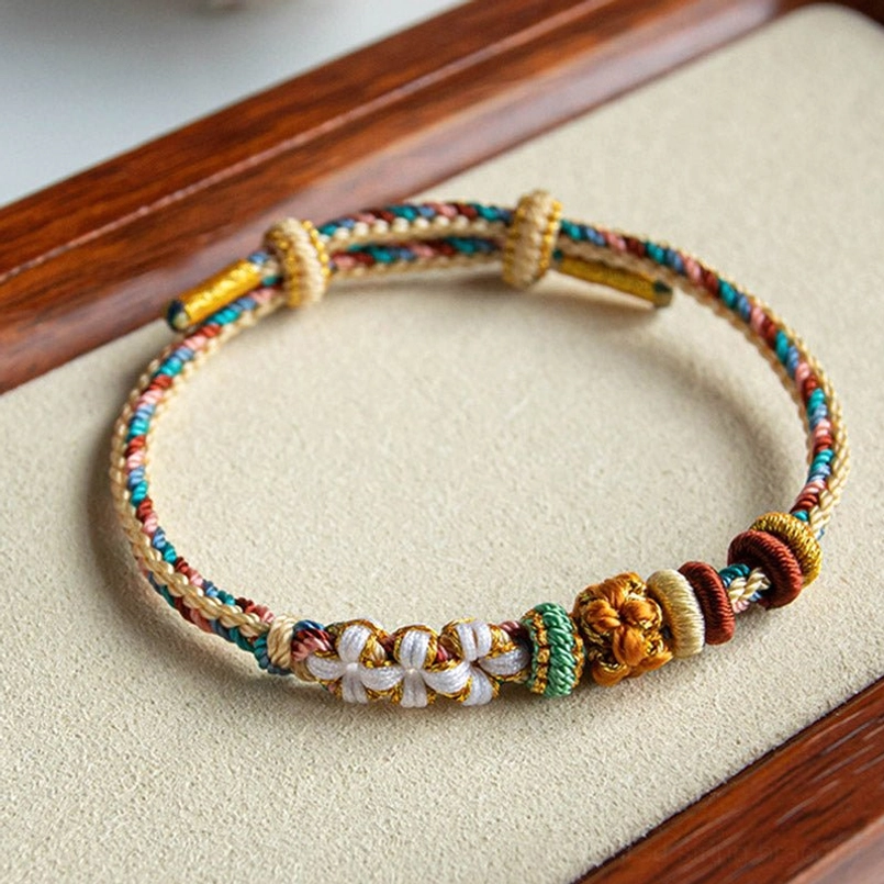 Handwoven peach blossom braided bracelet with gold metallic thread accents and adjustable flower knot closure