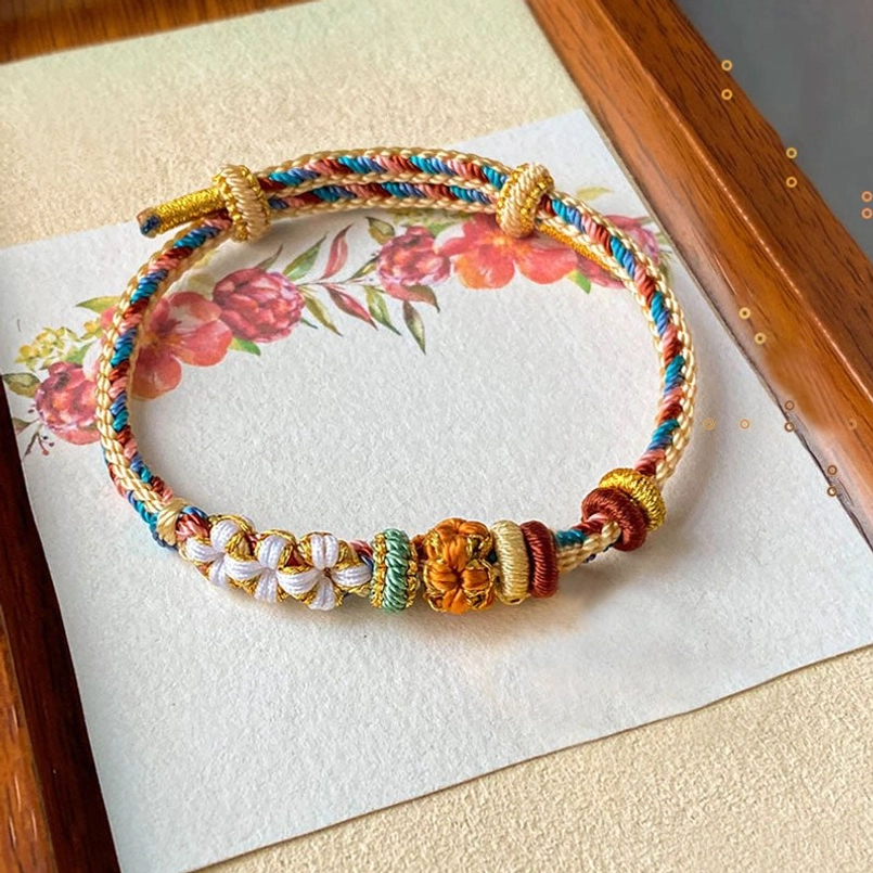 Dunhuang style peach blossom braided bracelet with warm earthy color woven threads and floral decorative elements