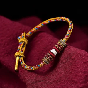 Handmade Dunhuang color luck braid string bracelet close-up view with ornate knot on maroon cloth