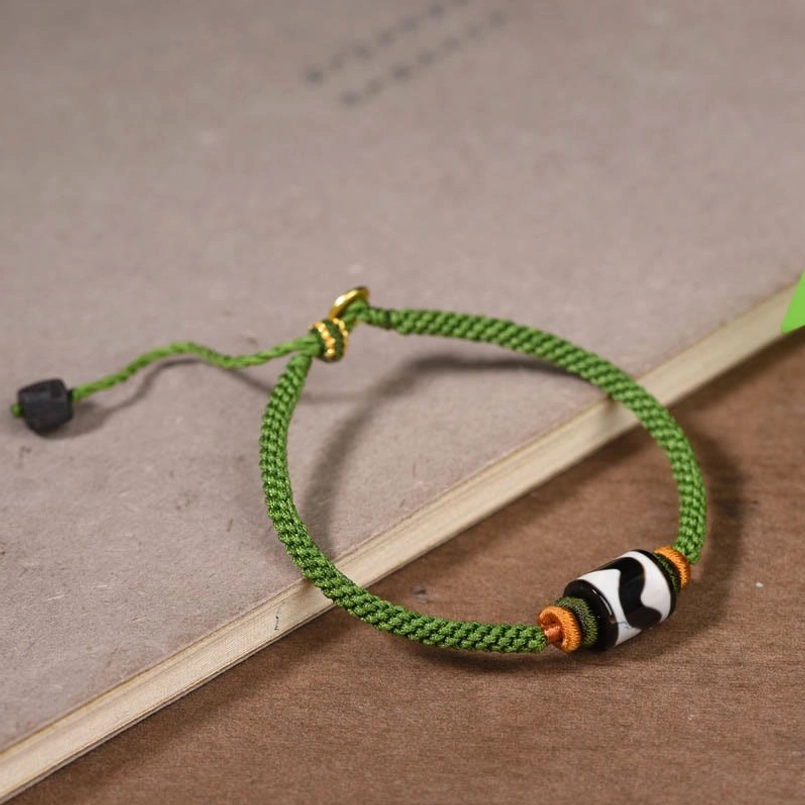 Tibetan Dzi bead green rope bracelet with orange spacers and black sliding knot adjustment