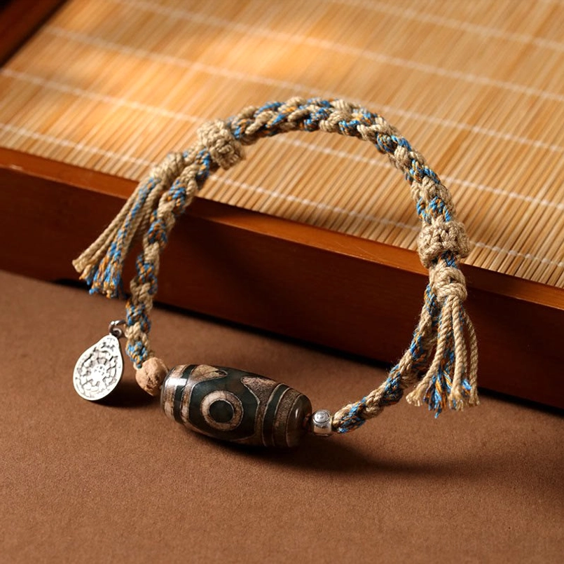 Dzi Bead fortune bracelet side view on wooden surface with tassel