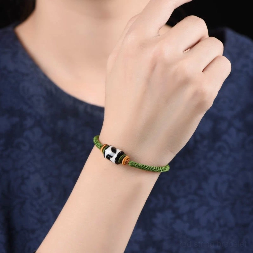 Worn Tibetan Dzi bead green rope protection bracelet on wrist showing minimalist daily style