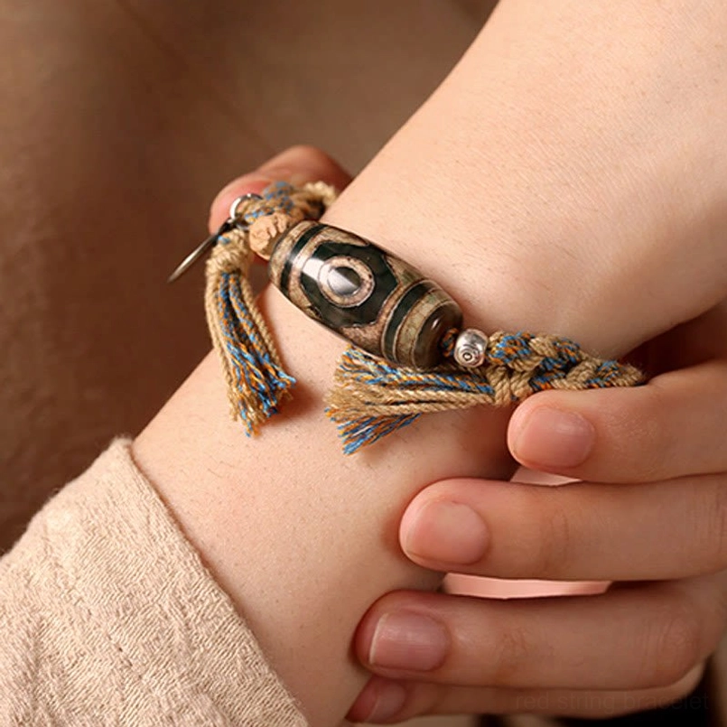 Close up view of Tibetan Dzi Bead red string bracelet worn on human wrist